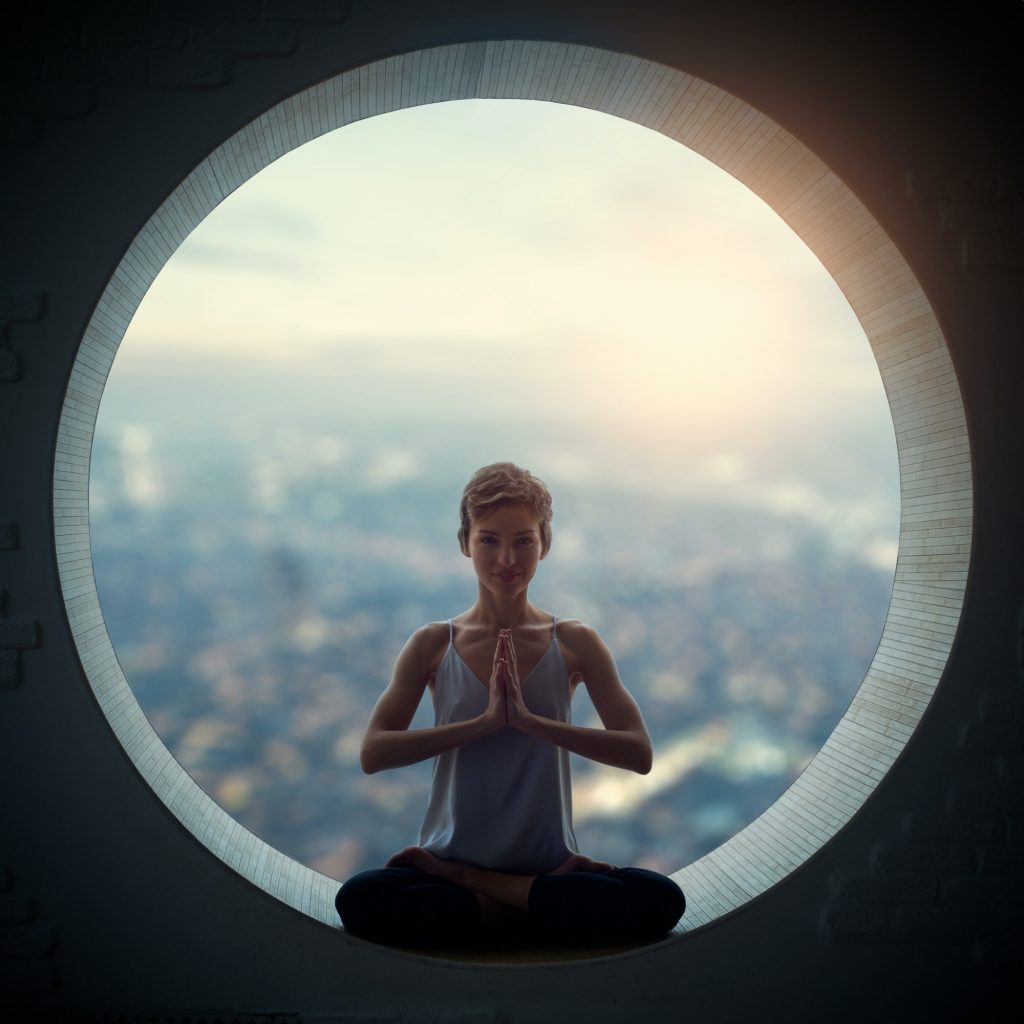 Beautiful sporty fit yogi woman practices yoga asana Padmasana - Lotus pose in a round window